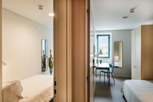 una camera da letto con due letti e un tavolo in una stanza di micampus Covilhã a Covilhã