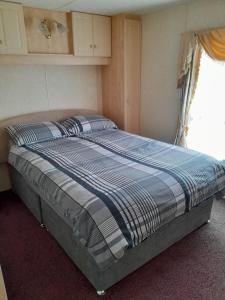 a bed sitting in a bedroom with a window at Mablethorpe L17 Caravan in Mablethorpe