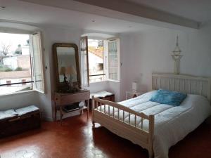 een slaapkamer met een bed, een spiegel en ramen bij Maison atypique corse in Bastia