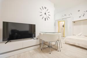a white living room with a large tv and a chair at Cozy studio Cvita in Zadar