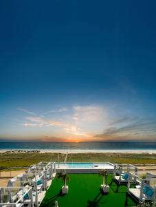 een resort met een zwembad en stoelen en de oceaan bij Hotel Pozo del Duque in Zahara de los Atunes