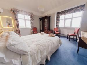 a bedroom with a large white bed and two windows at Hillside in Ardmore