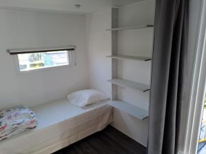 a small bedroom with a bed and shelves at Camping le Bois Jahan in Brunelles +62 photos