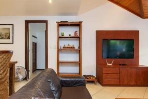 uma sala de estar com um sofá e uma televisão de ecrã plano em Praia da Ferradura com quatro suítes e piscina. em Búzios