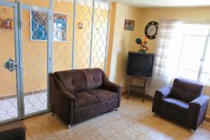 ein Wohnzimmer mit einem Sofa, einem Stuhl und einem TV in der Unterkunft Excelente para Grupos! 5 min al centro, sólo 2.7km in Puebla