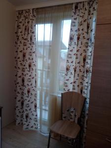a chair in front of a window with curtains with dogs at Хостел Атлас - Hostel Atlas in Blagoevgrad