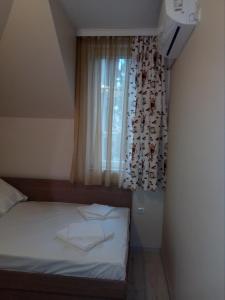 a small bedroom with a bed with a window at Хостел Атлас - Hostel Atlas in Blagoevgrad