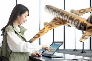 a woman standing at a table with a laptop at OMO Kansai Airport by Hoshino Resorts in Izumi-Sano