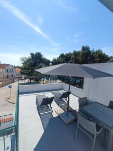 une terrasse avec une table, des chaises et un parasol dans l'établissement Apartments Paola, à Tribunj