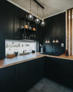eine Küche mit schwarzen Wänden und Holzoberflächen in der Unterkunft Halacs Homes Boutique Cabins, Unique cabin in Balatonalmádi
