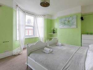 um quarto com paredes verdes e uma cama com toalhas em Cute and Cosy 2 Bed on a Peaceful street em Kent