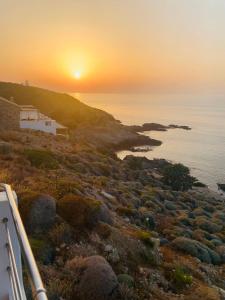 um pôr-do-sol sobre o oceano com uma casa numa colina em κοχύλι 1 em Armenistis