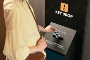 a man is holding a tie in front of a sign at OMO Kansai Airport by Hoshino Resorts in Izumi-Sano