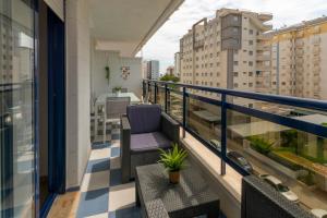 een balkon met een stoel en uitzicht op de stad bij AG RESIDENCIAL EL EDEN in Playa de Gandia