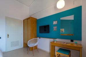 um quarto com uma parede azul, uma secretária e um espelho. em Elite Corfu Sea View Rooms em Corfu Town
