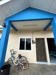 a bike parked outside of a house with a blue roof at Mahasa Penarik Homestay in Kampong Ru Sepuloh