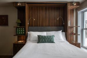1 dormitorio con cama blanca y almohada verde en Maison de Vébron, en L'Anse-Saint-Jean