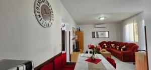 ein Wohnzimmer mit einem roten Sofa und einer Uhr an der Wand in der Unterkunft Andela Apartment in Pula