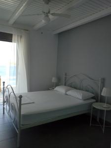 1 dormitorio con cama blanca y ventana en the South Breeze en Karistos