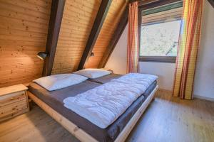ein Schlafzimmer mit einem Bett in einem Zimmer mit einem Fenster in der Unterkunft Ferienwohnpark Immenstaad am Bodensee Nurdachhaus Typ 8 NDT 036 in Immenstaad am Bodensee