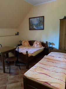 a bedroom with two beds and a table and a table at Dom Pod Dębem in Majdy