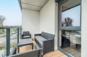 een balkon met 2 stoelen, een tafel en een raam bij Bridge Apartments & Spa Dziwnów in Dziwnów
