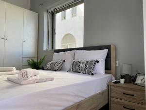 Cette chambre comprend un grand lit blanc avec des oreillers et une fenêtre. dans l'établissement Brand new apartment, in the heart of Kos '4', à Kos