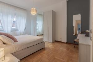 a bedroom with a white bed and a wooden floor at Como Borghi Apartment by Wonderful Italy in Como