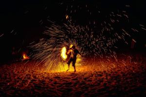 a man standing on a beach with a fire at VIP Suite Seaview Batu Ferringhi 1003-2 Bedroom in Batu Ferringhi