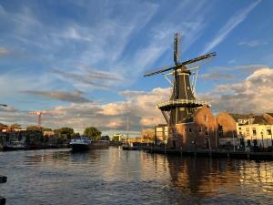 um moinho de vento sentado na água ao lado de um rio em Lowlander BnB em Heemskerk