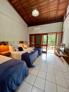 a bedroom with two beds and a large window at Recanto Verde Praia Hotel Juquehy in Juquei