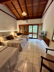 een kamer met drie bedden en een televisie. bij Recanto Verde Praia Hotel Juquehy in Juquei