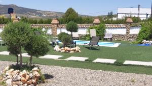 un patio trasero con piscina, sillas y un árbol en Villa Minerva, en Arriate