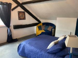 um quarto com uma cama azul num sótão em Chambres d'Hôtes de la forge em Oradour-Saint-Genest