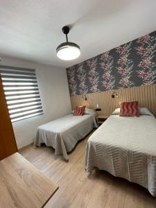 a room with two beds and a wall with flowers at Hostal Calderón de la Barca in Zalamea de la Serena