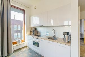 ミエンジズドロイェにあるW Rent like home - Tulipan Penthouse IIIの白いキャビネット、シンク、窓付きのキッチン