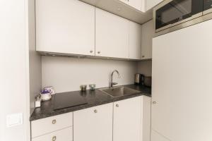 a kitchen with white cabinets and a sink at Międzyzdroje Horyzont - Apartament z Klimatyzacją i Balkonem by Renters in Międzyzdroje