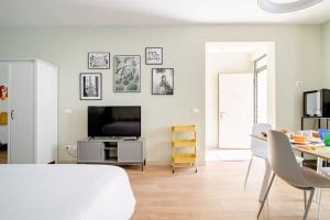 ein weißes Wohnzimmer mit einem Tisch und einem TV in der Unterkunft B&B Franciacorta Rodengo Saiano in Rodengo Saiano