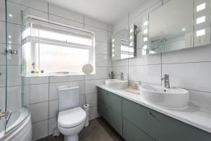 a white bathroom with two sinks and a toilet at Stylish North Cambridge 4 bed House in Milton