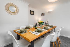 a dining room with a wooden table and white chairs at Stylish North Cambridge 4 bed House in Milton