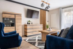 a living room with a desk and blue chairs at Apartamenty Rodzinne ApartZakop in Zakopane