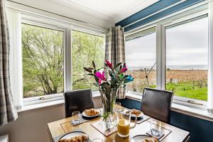 a dining room with a table and chairs and a large window at The Pink Bungalow in Dingwall