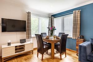 a dining room with a table and chairs and a tv at The Pink Bungalow in Dingwall