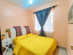 Modern & Comfy Mt. Kenya Sunset View Apartment في Kangaru: غرفة نوم بسرير اصفر ونافذة