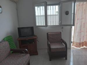 ein Wohnzimmer mit 2 Stühlen und einem TV in der Unterkunft Confortable Maisonnette prés de la plage à Dar el Alouch in Kelibia