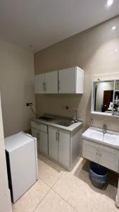 a kitchen with white cabinets and a sink and a mirror at اضواء السلام للشقق المخدومة in Medina