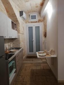 una cocina con armarios blancos y una puerta azul en VIA MAGNO, en Monopoli