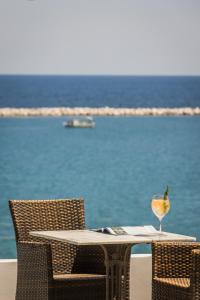 Griffon Kymi Hotel previously known as Valledi Village في كيمي: طاولة مع كأس نبيذ وكراسي على الشاطئ