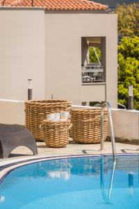 a swimming pool with wicker baskets next to a house at Griffon Kymi Hotel previously known as Valledi Village in Kymi