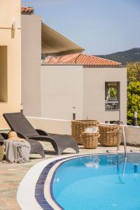 a swimming pool with chairs and a house at Griffon Kymi Hotel previously known as Valledi Village in Kymi